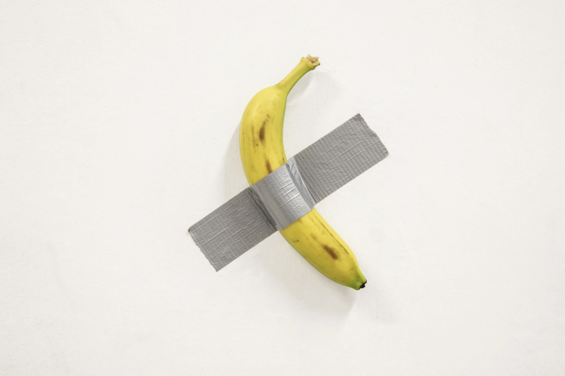 Image de l'oeuvre de Maurizio Cattelan représentant une banane accrochée au mur avec du ruban adhésif