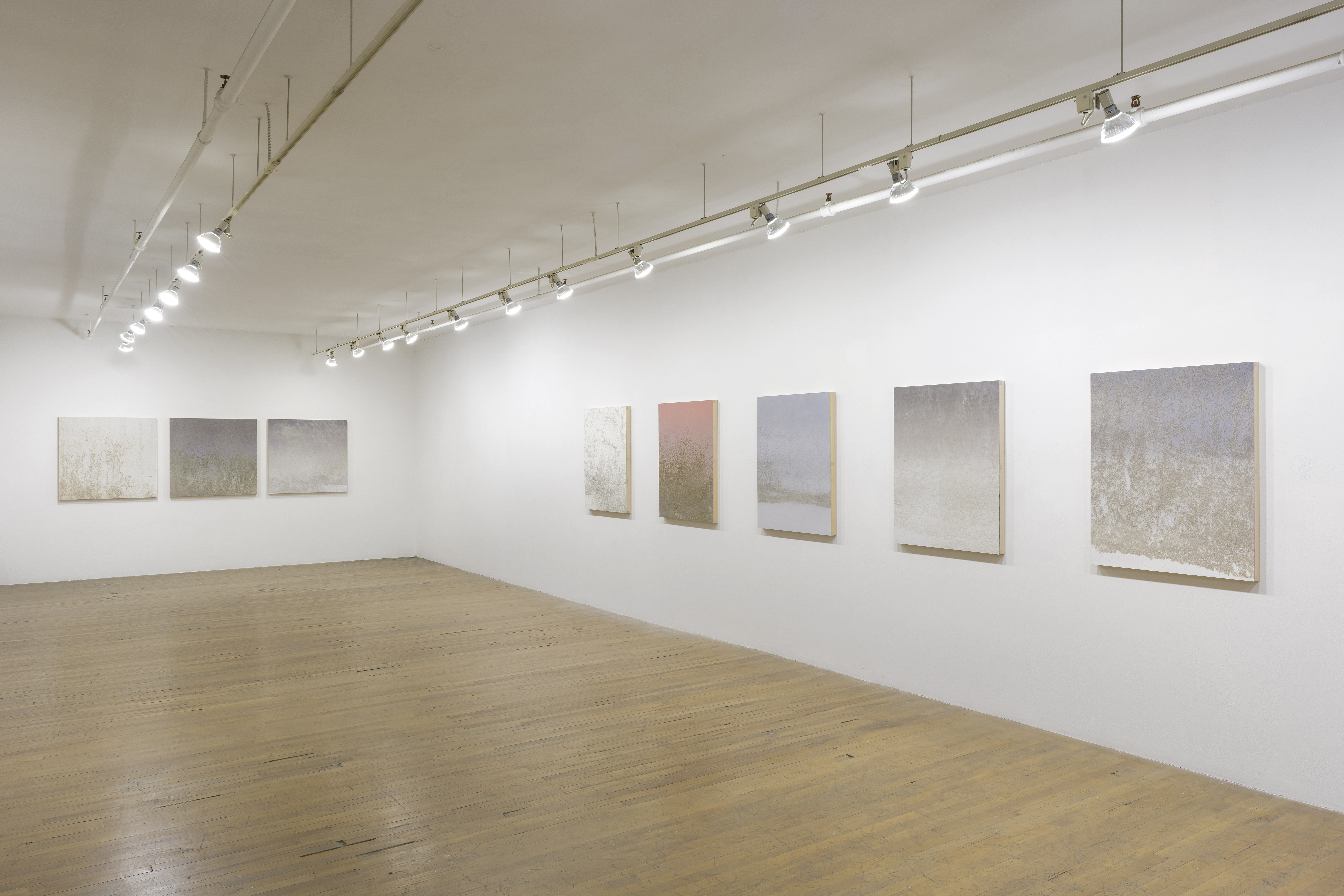 Vue de l’exposition à la Galerie Bellemare Lambert : peintures accrochées sur des murs blancs dans un espace lumineux, plancher en bois ©Guy L’Heureux